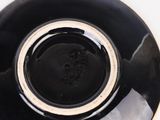 a black bowl with a white rim on a white surface