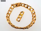gold bracelet with a clasp and a ring on a white surface