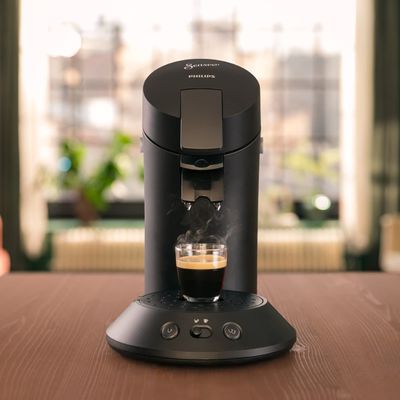une cafetière posée sur une table, à côté d'une tasse de café