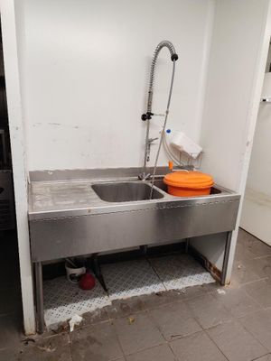 a sink in the corner of a room with a faucet in it