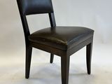 the back of a black leather dining chair against a white backdrop