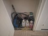 une photo d'une petite pièce où se trouvent un aspirateur et d'autres articles ménagers