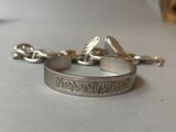 a silver bracelet with a coin on it on a table