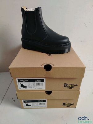 black leather boots are stacked on top of boxes on a white floor