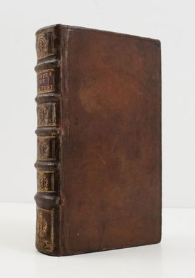 un vieux livre marron posé sur une table blanche