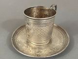 une tasse et une soucoupe en argent posées sur une soucoupe