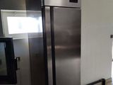 a stainless steel refrigerator in a kitchen with tile flooring