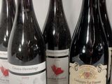 six bottles of red wine are lined up on a table