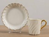 a white cup and saucer sitting on a table