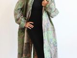 woman in a black dress and green jacket posing for a picture