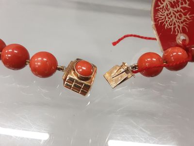an image of a necklace with a red bead and a gold clasp