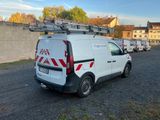 une camionnette blanche garée sur un parking, avec une échelle sur le toit