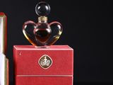 two perfume bottles sitting on top of a red box next to each other