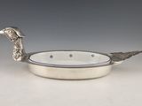 a silver plate with a bird on it on a table