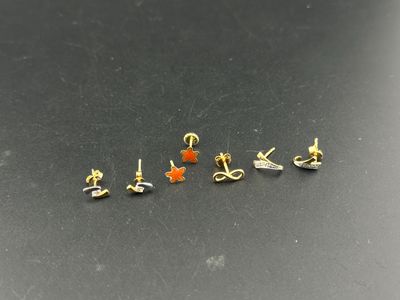 a close up of a small assortment of earrings on a black surface
