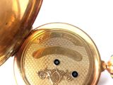 a close up of a gold pocket watch on a white surface