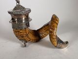 an antique silver plated pipe with a wooden handle on a white surface