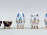 four different colored egg shaped vases sitting next to each other on a white surface