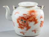 a white tea pot with a red design on it