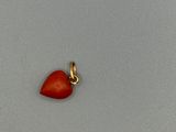 une image représentant un pendentif en forme de cœur rouge sur une surface grise