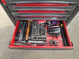 une boîte à outils contenant des outils, posée sur le sol