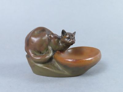 a small statue of a cat sitting on top of a bowl