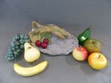 une figurine représentant un lézard assis sur un rocher, entouré de fruits et de légumes