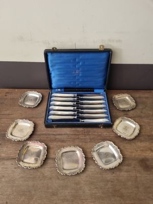 a set of six silver plated knives in a case on a table
