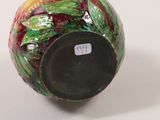 a colorful vase with a black lid sitting on a white surface