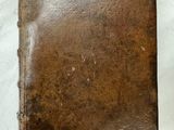 un vieux livre en cuir marron posé sur une table blanche