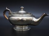 a silver tea pot on a black table