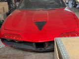 une voiture de sport rouge garée dans un garage, avec d'autres voitures en arrière-plan