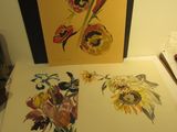 trois tableaux représentant des fleurs posées sur une table à côté d'une lampe