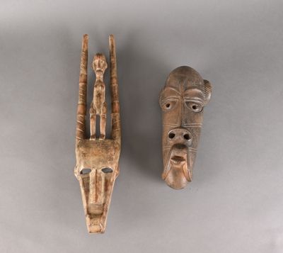 deux masques en bois sculptés sur un fond gris