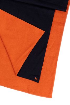 L'écharpe orange et noire est pliée sur la couverture noire et orange.