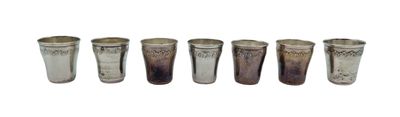 six different shot glasses lined up in a row on a white background
