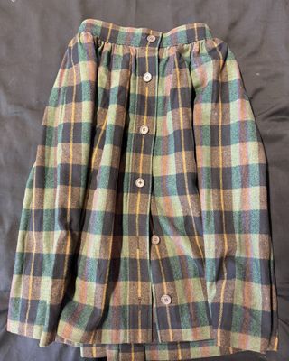 un gros plan sur une chemise et une jupe à carreaux posées sur un lit