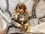 a doll sitting on a bed with a sign on it