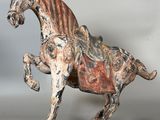 statue of a horse on a wooden base on a gray background