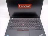 the laptop is open on a white surface with a red lenovo logo on the screen