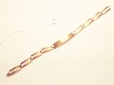 a gold bracelet on a white surface with a price tag