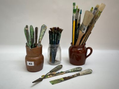 de nombreux pinceaux et un pot de peinture sur la table