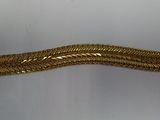 gros plan d'un bracelet en or sur une surface blanche