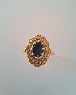 gros plan d'une bague en or avec une pierre en saphir