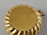 a close up of a gold plated pendant on a white surface
