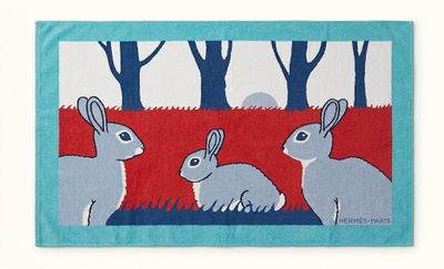 a blue and red rug with two rabbits in the woods