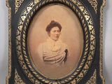 an old picture of a woman in a white dress in a black frame