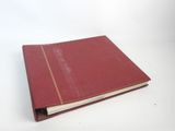 un vieux livre rouge posé sur une table blanche