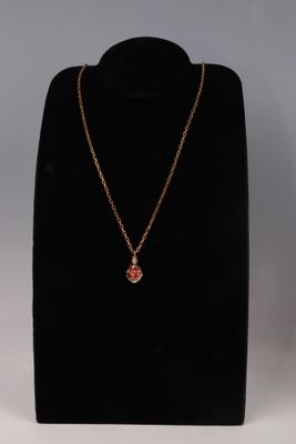 un collier en or orné d'une pierre rouge sur un mannequin noir