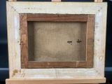 an old picture frame with a cross on it sitting on a wooden stand